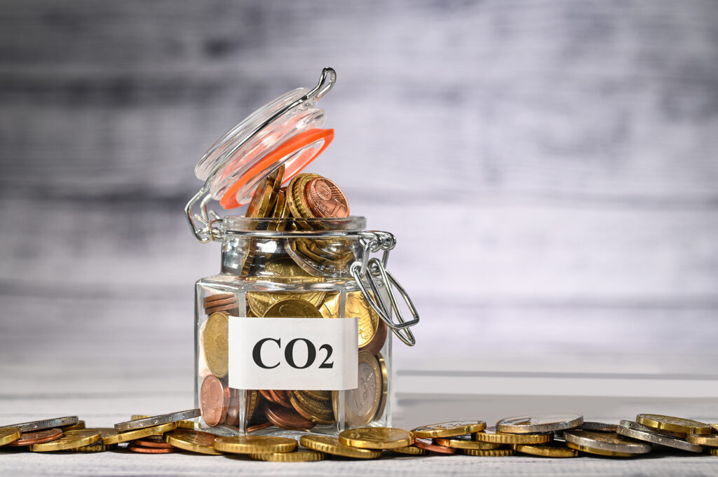 Glas mit Aufschrift CO2 darin und daneben Euromünzen