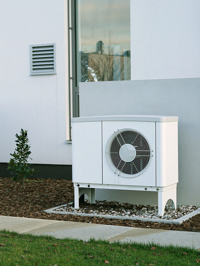 weiße Wärmepumpe vor einem Haus