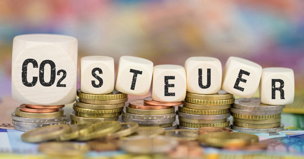 Würfel bilden das Wort CO2-Steuer und liegen auf Euromünzen